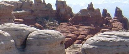Rock formations with rounded, layered structures in a rugged landscape, featuring tall spires and a clear blue sky in the background. Klondike Bluffs mountain bike trail.