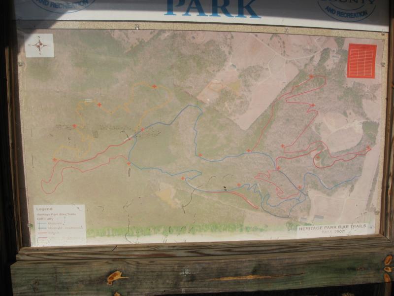 Map of Heritage Park bicycle trails, displaying various routes marked in red, blue, and yellow indicating different difficulty levels. Includes a legend for trail identification and a compass rose for orientation. Heritage Park mountain bike trail.