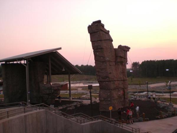 Rock climbing facility at dusk, featuring two large climbing walls with a nearby shelter, surrounded by landscaped areas and trees in the background. USNWC mountain bike trail.