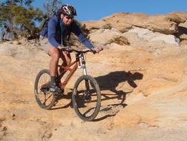 A mountain biker navigating a rocky terrain under a clear blue sky, showcasing an action shot of outdoor biking adventure. Palmer Park mountain bike trail.