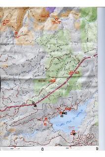 Topographic map featuring mountainous terrain with elevation contours, marked trails, and a water body. The map includes symbols indicating points of interest and pathways, with various colors denoting different land elevations and vegetation. Pioneer Trail mountain bike trail.