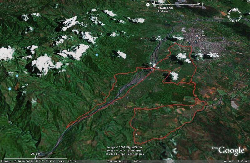 A 3D satellite image showing a mountainous region with snow-capped peaks, a river running through the valley, and a town labeled "Bonao." The image showcases green landscapes and outlines of geographical features, with a red boundary indicating a specific area of interest. The date and time of the image capture are displayed at the top. Cordillera Central mountain bike trail.