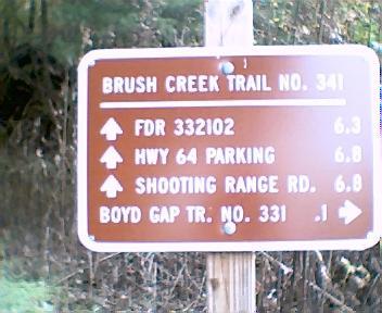 Brown trail sign indicating directions and distances to various locations: Brush Creek Trail No. 341, FDR 332102 (6.3 miles), HWY 64 Parking (6.8 miles), Shooting Range Rd (6.8 miles), and Boyd Gap Trail No. 331 (0.1 miles). Brush Creek mountain bike trail.