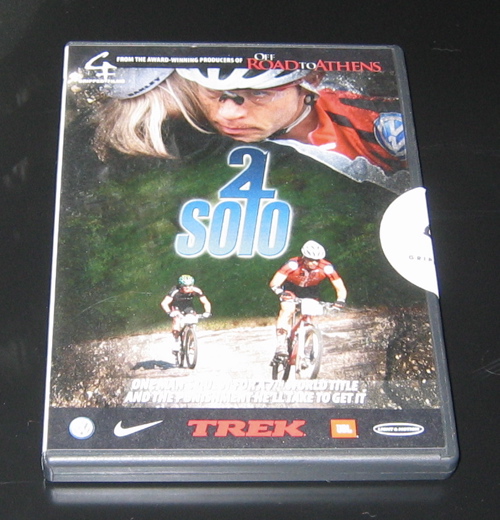 A DVD cover for the film "2 Solo," featuring a close-up of a cyclist wearing a helmet and sunglasses, along with two mountain bikers riding on a dirt path. The title "2 Solo" is prominently displayed in blue, and the cover also includes branding from sponsors like Nike and Trek, as well as a note that it is from the producers of "Off Road to Athens."