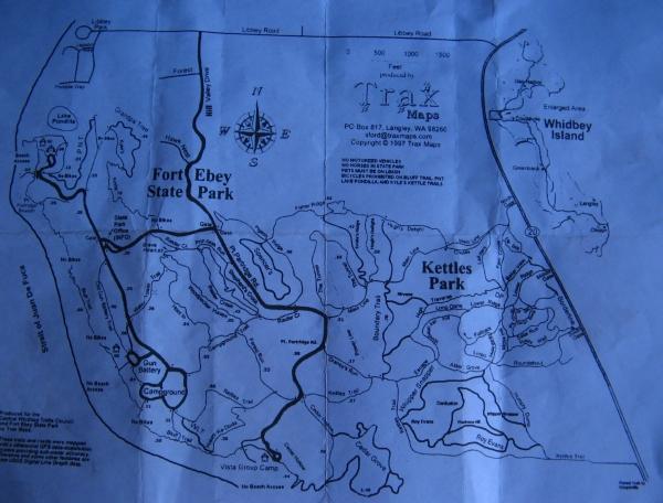 A detailed black-and-white map highlighting Fort Ebey State Park and Kettles Park on Whidbey Island, showing trails, roads, and various landmarks. The map includes a compass rose indicating the cardinal directions and a copyright notice from 1997. Fort Ebey St Park mountain bike trail.
