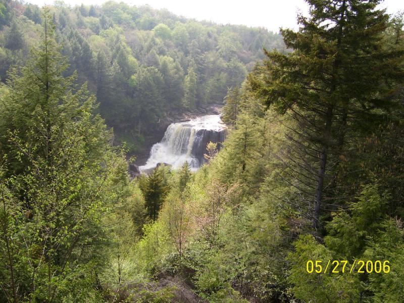 A picturesque view of a waterfall cascading down rocky cliffs, surrounded by lush green trees and foliage, captured in a serene natural setting. The image has a date stamp indicating May 27, 2006. CVI Trails mountain bike trail.