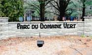 Sign marking the entrance to Parc du Domaine Vert, surrounded by trees and greenery. Parc Du Domaine Vert mountain bike trail.