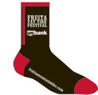 Black and red sock featuring the text "Fruita Fat Tire Festival" and the US Bank logo, along with a website URL for Fruita Mountain Bike.