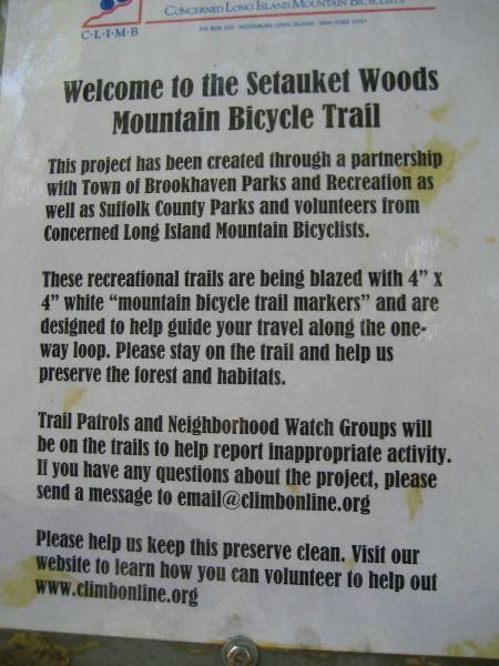 Welcome sign for the Setauket Woods Mountain Bicycle Trail, detailing a partnership with local parks and mountain bicyclists. The sign explains trail markers and encourages visitors to stay on the trail while preserving the forest. It also mentions Trail Patrols and a contact email for inquiries, along with a reminder to keep the preserve clean. East Setauket mountain bike trail.