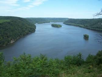 A scenic view of a river winding through lush green hills, with several small islands visible on the water