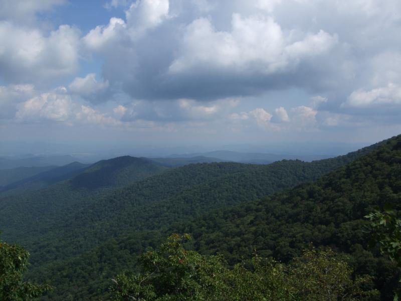 A panoramic view of lush green mountains under a partly cloudy sky, with layers of rolling hills fading into the distance. Laurel Mountain mountain bike trail.