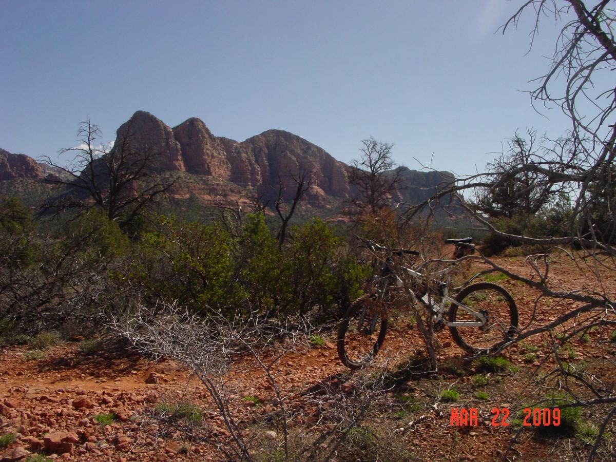 A mountain bike parked in a rugged landscape with red rock formations in the background, surrounded by sparse vegetation and trees. The image is taken on a clear day with a blue sky. The date in the bottom corner indicates March 22, 2009. Templeton mountain bike trail.
