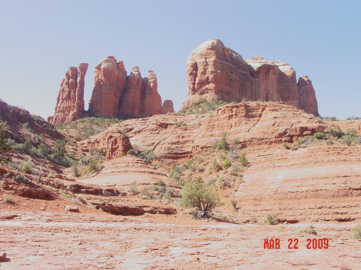 Tall red rock formations rise prominently against a clear blue sky, surrounded by rugged terrain and sparse greenery typical of a desert landscape. The image captures the natural beauty and unique geology of the area. The date "Mar 22, 2009" is visible in the lower right corner. Templeton mountain bike trail.