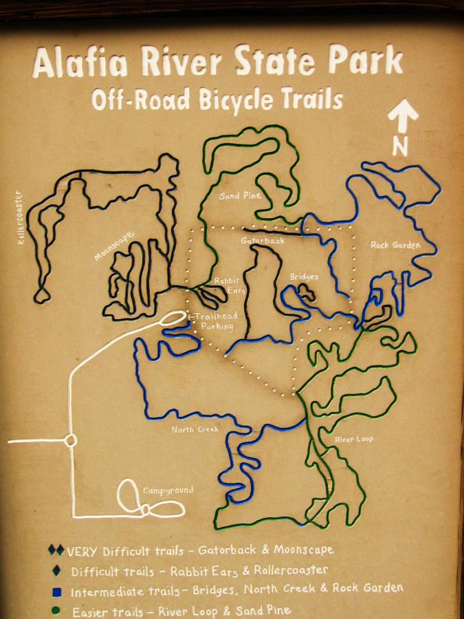 Map of Alafia River State Park showing off-road bicycle trails. Various trails are marked in different colors, indicating levels of difficulty: very difficult (dark blue), difficult (light blue), intermediate (green), and easier (light green). Key locations include trailhead parking, campgrounds, and specific trails like Rabbit Ears, Bridges, and Rock Garden. North is indicated at the top of the map. Alafia River State Park mountain bike trail.