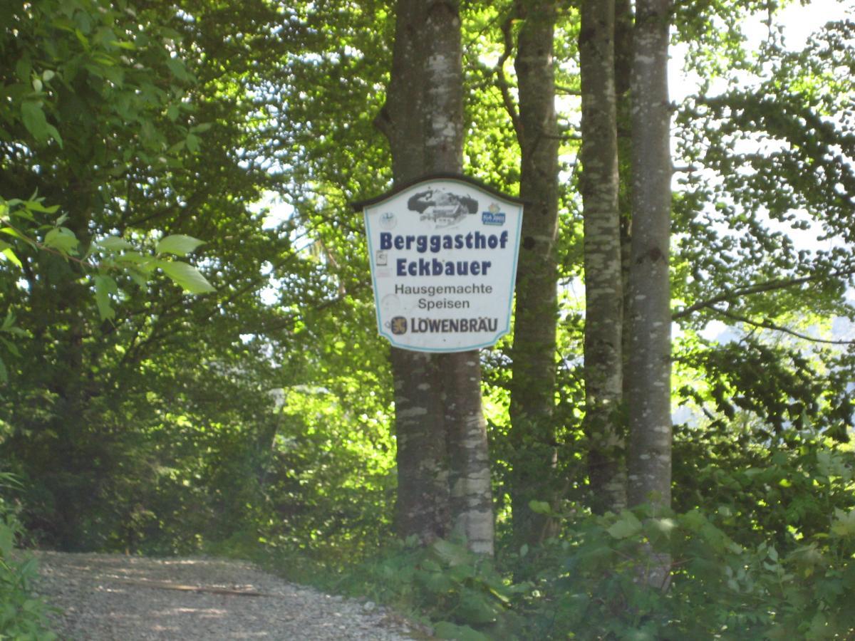 Sign for Berggasthof Eckbauer, surrounded by trees, indicating homemade dishes and featuring the Löwenbräu logo. Garthof Partnachklamm Trail mountain bike trail.