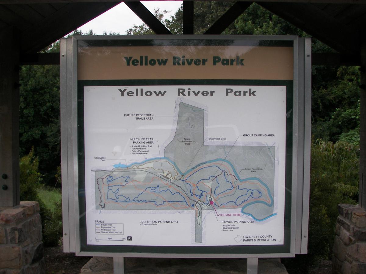 Map of Yellow River Park displayed on a sign, showing trails, parking areas, and park features, including a group camping area and an observation deck. Yellow River mountain bike trail.
