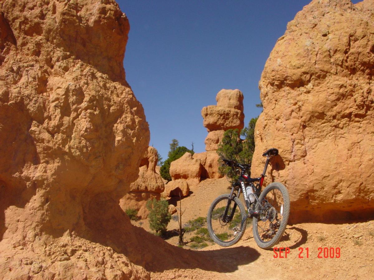 A mountain bike is parked on a dirt trail surrounded by orange rock formations and a clear blue sky. The scene features large, textured rocks with varying shapes and sizes, showcasing a natural landscape ideal for outdoor activities. The date in the corner indicates September 21, 2009. Thunder Mountain mountain bike trail.