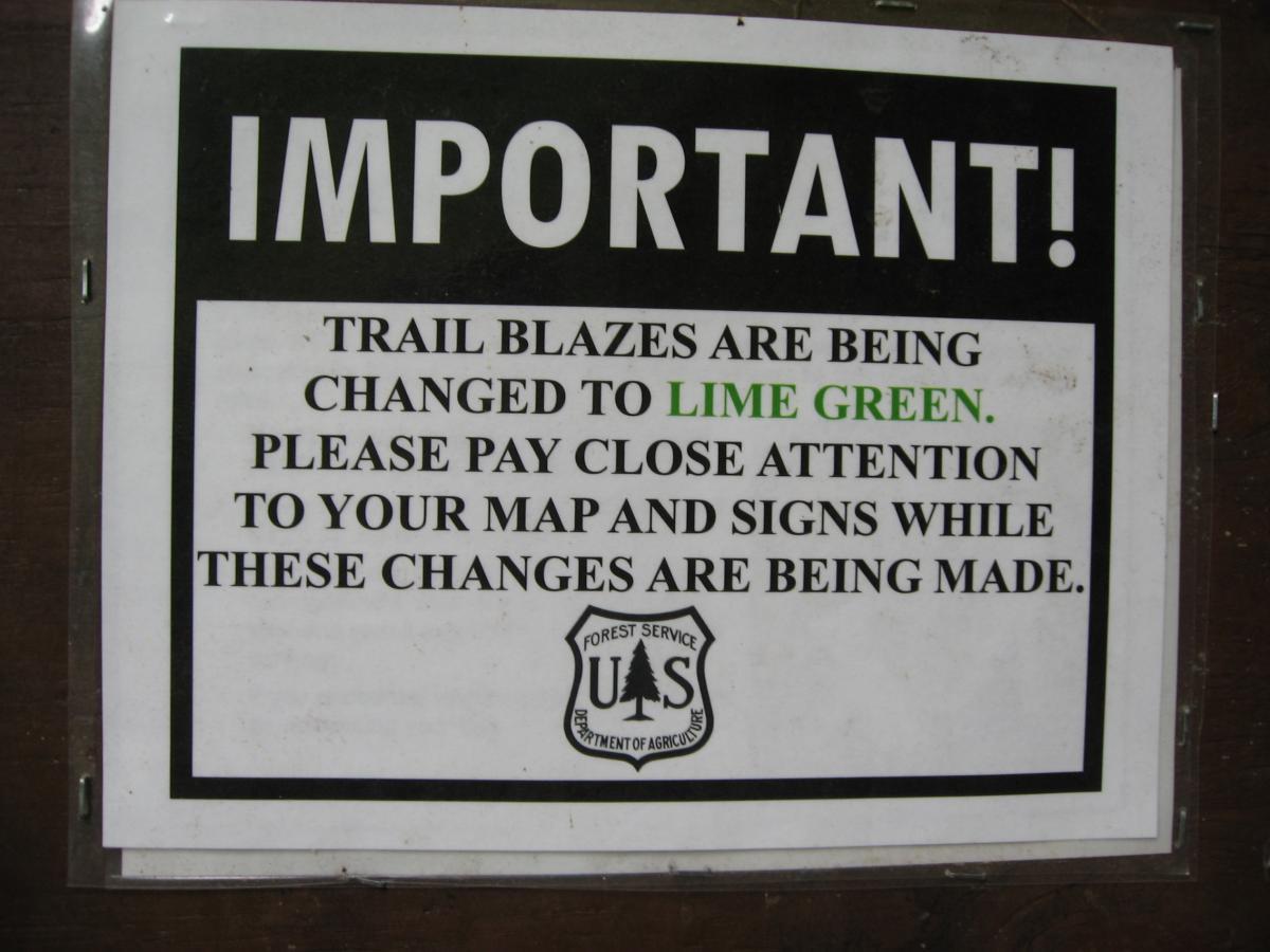 Sign indicating that trail blazes are being changed to lime green, with a note to pay close attention to maps and signs during this transition. The sign features the U.S. Forest Service logo. Stanley Gap mountain bike trail.
