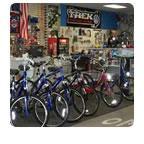 Image of a bicycle shop interior displaying several bicycles in various colors, including blue and red. The walls are decorated with bicycle-related accessories and memorabilia, and there is a prominent sign in the background.