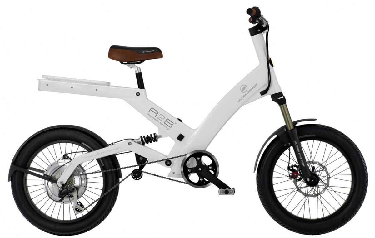 Alt text: A modern white electric bike with a simple design, featuring a brown seat, thick black tires, and a visible electric motor. The bike has a sleek frame with a cushioned suspension system and a minimalist look.