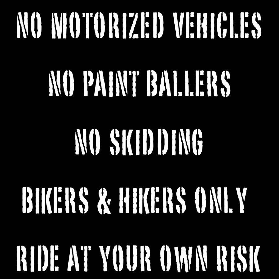 Black sign with white, bold text listing trail regulations: "No Motorized Vehicles," "No Paint Ballers," "No Skidding," "Bikers & Hikers Only," and "Ride at Your Own Risk." Games Loop mountain bike trail.