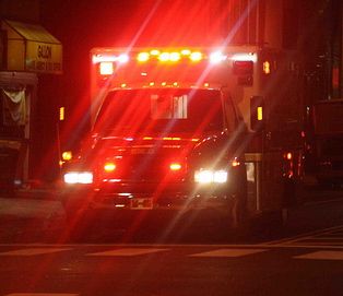 Emergency ambulance with flashing lights at night, responding to a call.