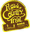 Logo for the Flow Country Trail, featuring stylized text in yellow on a brown background, with a circular design and mountain icons.