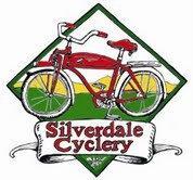 A logo featuring a red bicycle in front of a green and yellow diamond background, with the text "Silverdale Cyclery" on a white banner at the bottom.