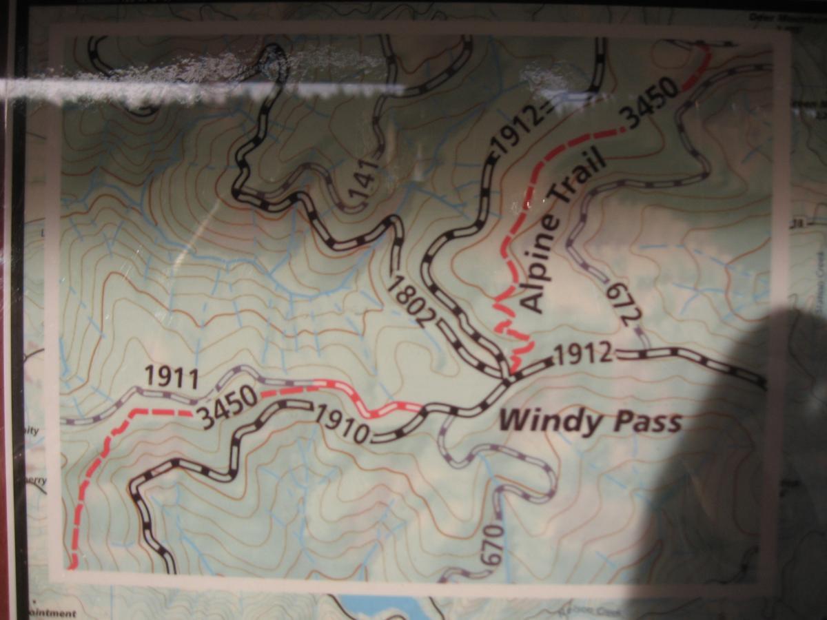 Map showing the Alpine Trail and Windy Pass with contour lines indicating elevation changes. Key route numbers, including 1911, 1912, and 1910, are marked, along with elevation points such as 3450. The map features winding trails and topographical details, suitable for hiking navigation. Alpine Trail mountain bike trail.