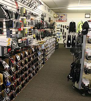 A well-organized bicycle shop interior featuring racks of helmets, accessories, and cycling gear displayed on shelves along the walls, with an aisle running through the center.