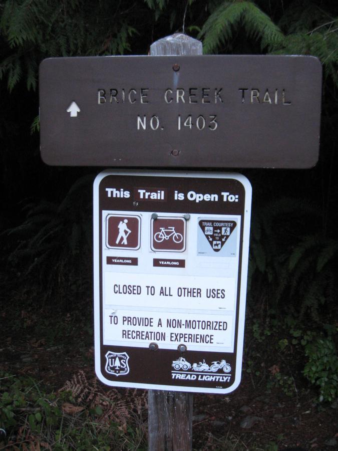 Sign for Brice Creek Trail No. 1403, indicating the trail is open for hiking and biking year-round, and closed to all other uses to promote a non-motorized recreation experience. The sign features Trail Courtesy symbols and the message "Tread Lightly!" along with official markings. Brice Creek mountain bike trail.
