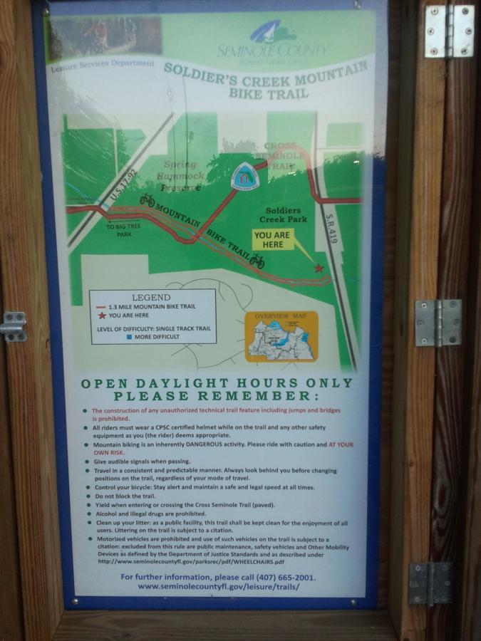 Map and information signage for Soldier's Creek Mountain Bike Trail located in Seminole County. The sign includes a trail map, difficulty levels, safety guidelines for cyclists, and contact information for further details. It highlights the trail's length of 1.3 miles and indicates nearby landmarks. Soldier Creek Park mountain bike trail.