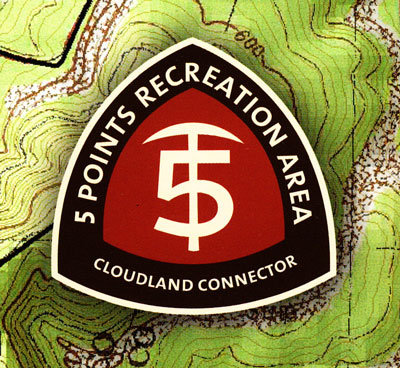 Logo for the 5 Points Recreation Area, featuring a stylized number 5 and the text "CLOUDLAND CONNECTOR" in a modern font, set against a background resembling a topographic map. The logo is enclosed in a triangular shape with a dark red and white color scheme.