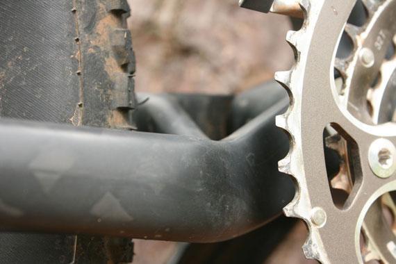 Blue Ryno Carbon: Close-up image of a bicycle's chainring and crankset, showing the connection to the bike frame and the tread on the tire, with dirt indicating off-road use.
