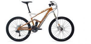 Cannondale Jekyll: A mountain bike with a light orange and silver frame, featuring wide tires and front suspension, positioned against a white background.
