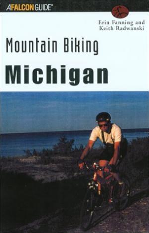 Falcon Guides Mountain Biking Michigan: A book cover for "Mountain Biking Michigan" featuring a cyclist riding on a trail with a coastal view. The title and authors