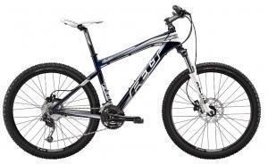 A mountain bike with a sleek design, featuring a dark blue and silver frame, disc brakes, and thick, rugged tires suitable for off-road terrain.