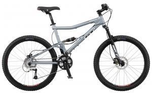 GT Marathon Sport: A silver mountain bike with a sturdy frame, dual suspension, and thick, textured tires designed for off-road trails. The bike features a comfortable saddle, handlebars with grips, and disc brakes for enhanced control.