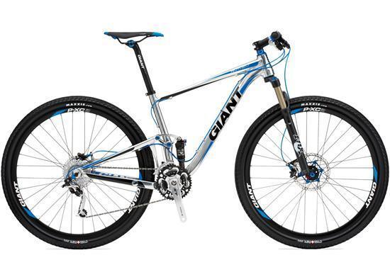 Giant Anthem X 29er 1: A modern mountain bike in a sleek design, featuring a silver and blue frame. The bike has two large, rugged tires with disc brakes and is equipped with a front suspension fork. The brand name "Giant" is prominently displayed on the frame.