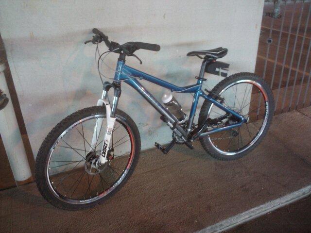 Giant Rincon: A blue mountain bike with thick tires, a silver frame, and a water bottle holder attached, leaning against a wall in an indoor setting.