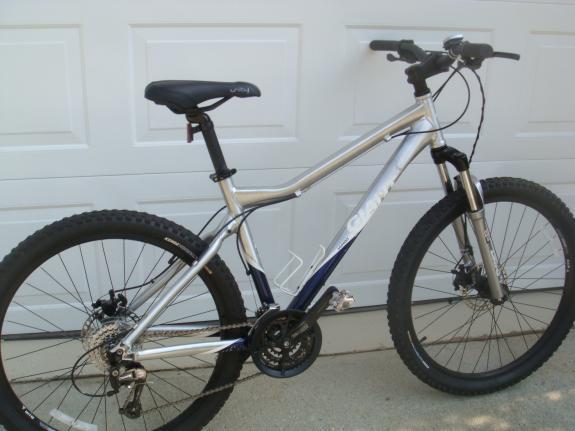 Giant Yukon: A silver and blue mountain bike with a sturdy frame, knobby tires, and a front suspension fork, positioned against a white garage door.