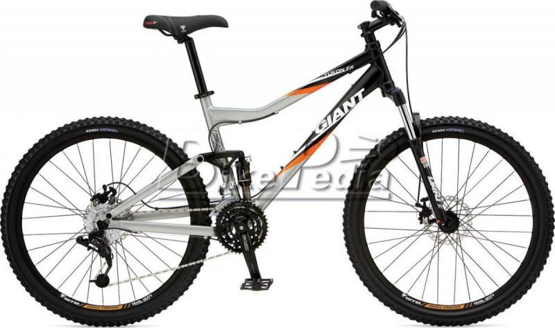Giant Yukon: Alt text: A Giant mountain bike featuring a silver and black frame with orange accents, equipped with thick tires and suspension for off-road riding. The bike is shown from the side, highlighting its design and components.