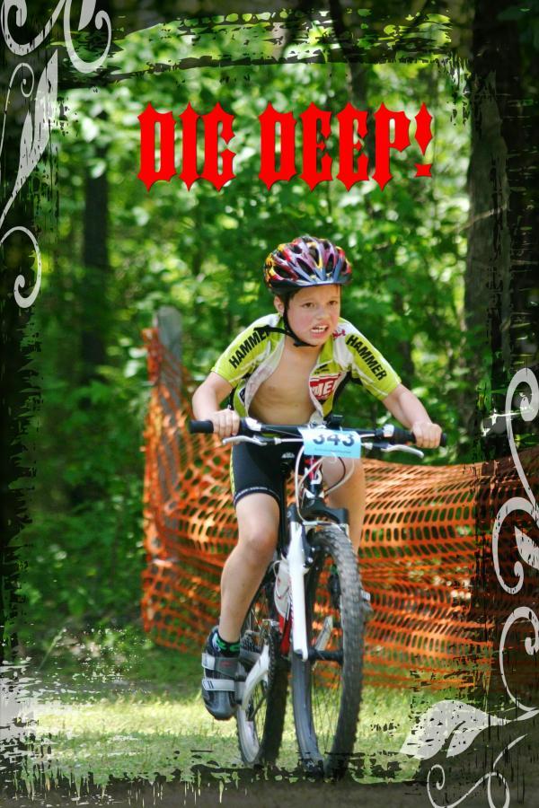 A young boy participates in a mountain biking race, displaying determination as he rides his bike on a grassy trail. He is wearing a sleeveless jersey and bike shorts, with a racing bib number visible on his front. The background features trees and an orange safety barrier, emphasizing the outdoor setting. The text "DIG DEEP!" is prominently overlaid in bold red letters. Harbison State Forest mountain bike trail.