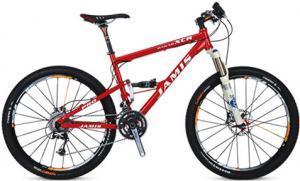 Jamis Dakar XCR Pro: A red mountain bike featuring a sturdy frame, front suspension, and disc brakes. The bike is equipped with multiple gears and has black tires with orange accents.
