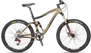 A modern mountain bike featuring a sleek black and gold frame, full suspension, wide tires, and disc brakes, set against a plain background.