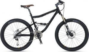 Jamis  Dakar XCT 3.0: A black mountain bike with a brown leather seat, featuring dual suspension, wide tires, and a gear system. The bike is positioned against a plain background.