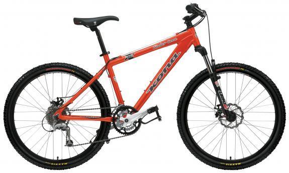 Kona Cinder Cone: An orange mountain bike with a sturdy frame, wide tires, and front suspension, featuring a Shimano gear system and disc brakes.