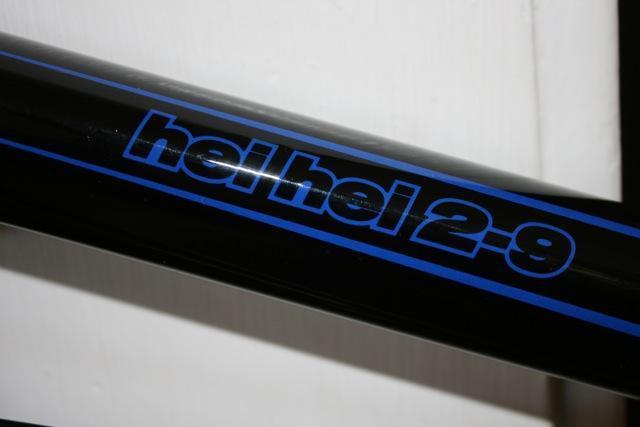 Kona Hei Hei 2-9: Image of a bicycle frame with the text "hel hel 2-9" in blue lettering against a black background.