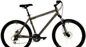 Motobecane 400HT: A silver mountain bike with wide tires, a black seat, and multiple gears, positioned against a white background. The bike features front suspension, disc brakes, and colorful accents on the rims.