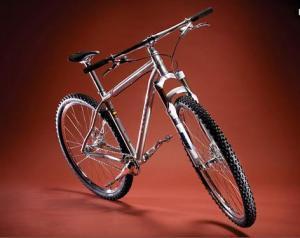 Niner One 9: A shiny silver mountain bike with thick tires, set against a rich red background. The bike is positioned at an angle to showcase its frame and components.